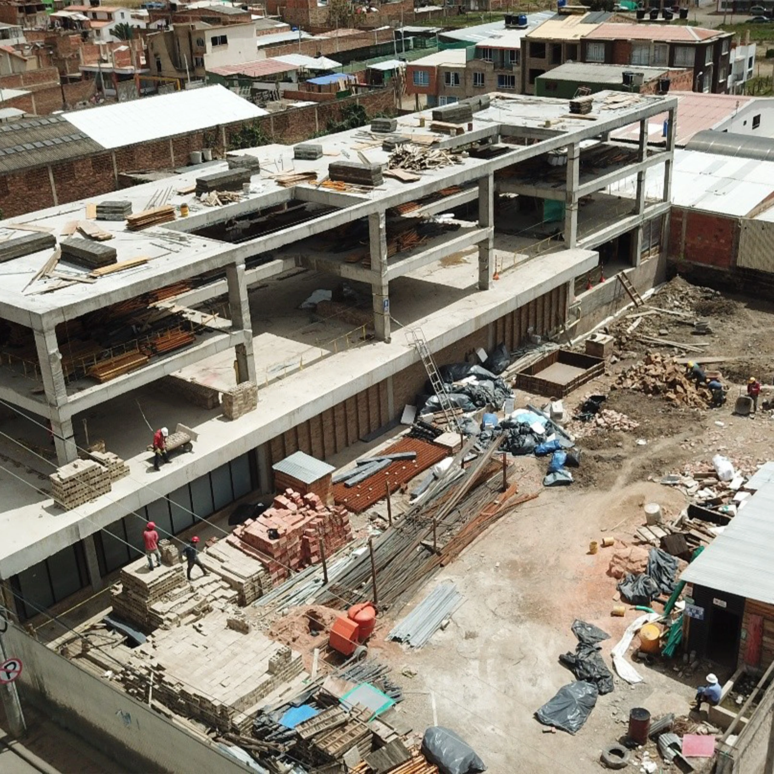 Obra: el pórtico de concreto y la mampostería de arcilla en pleno montaje, con el ritmo estructural que después ordena la fachada.