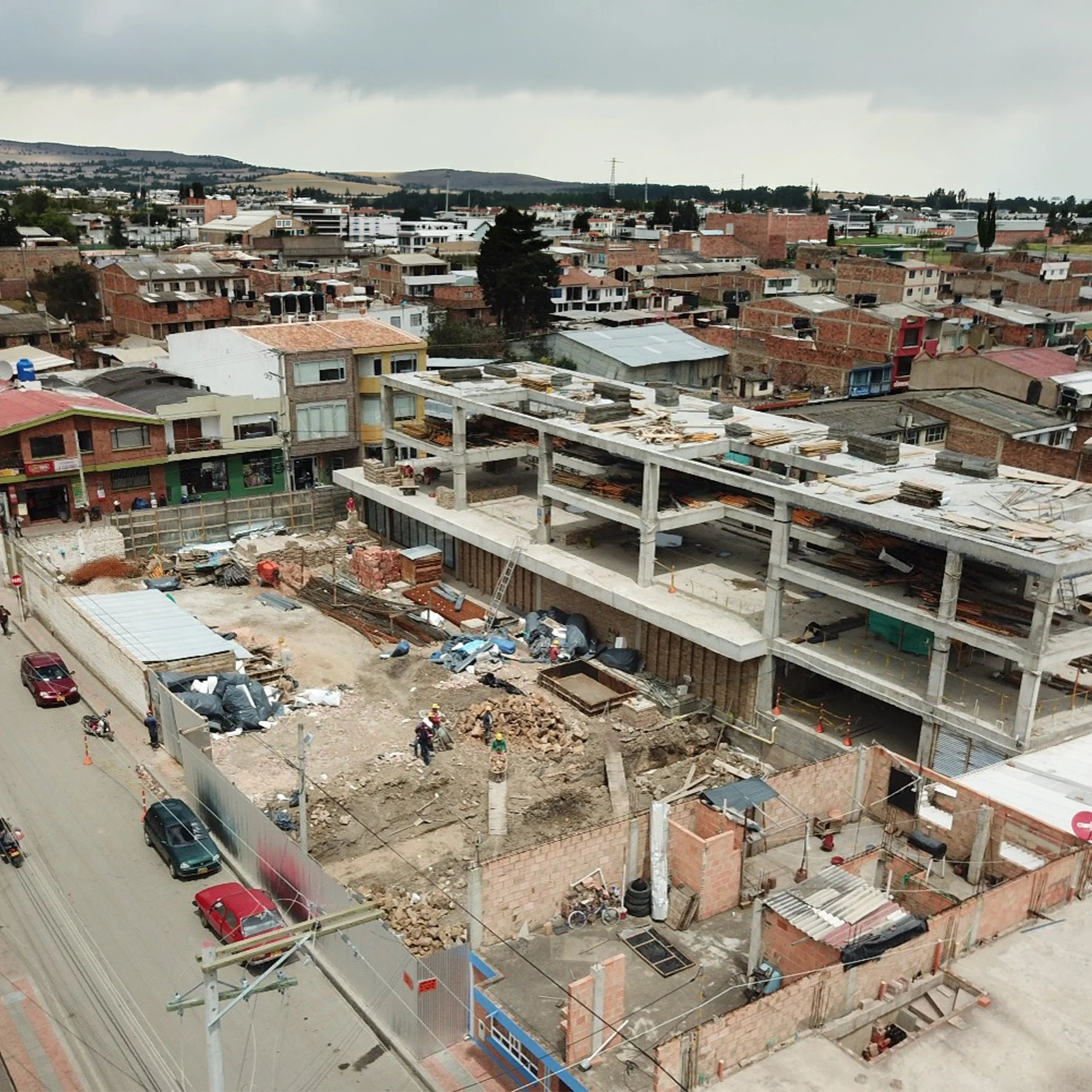 Obra en su contexto: el edificio creciendo dentro del tejido de casas bajas de Samacá, con las lomas del valle al fondo.