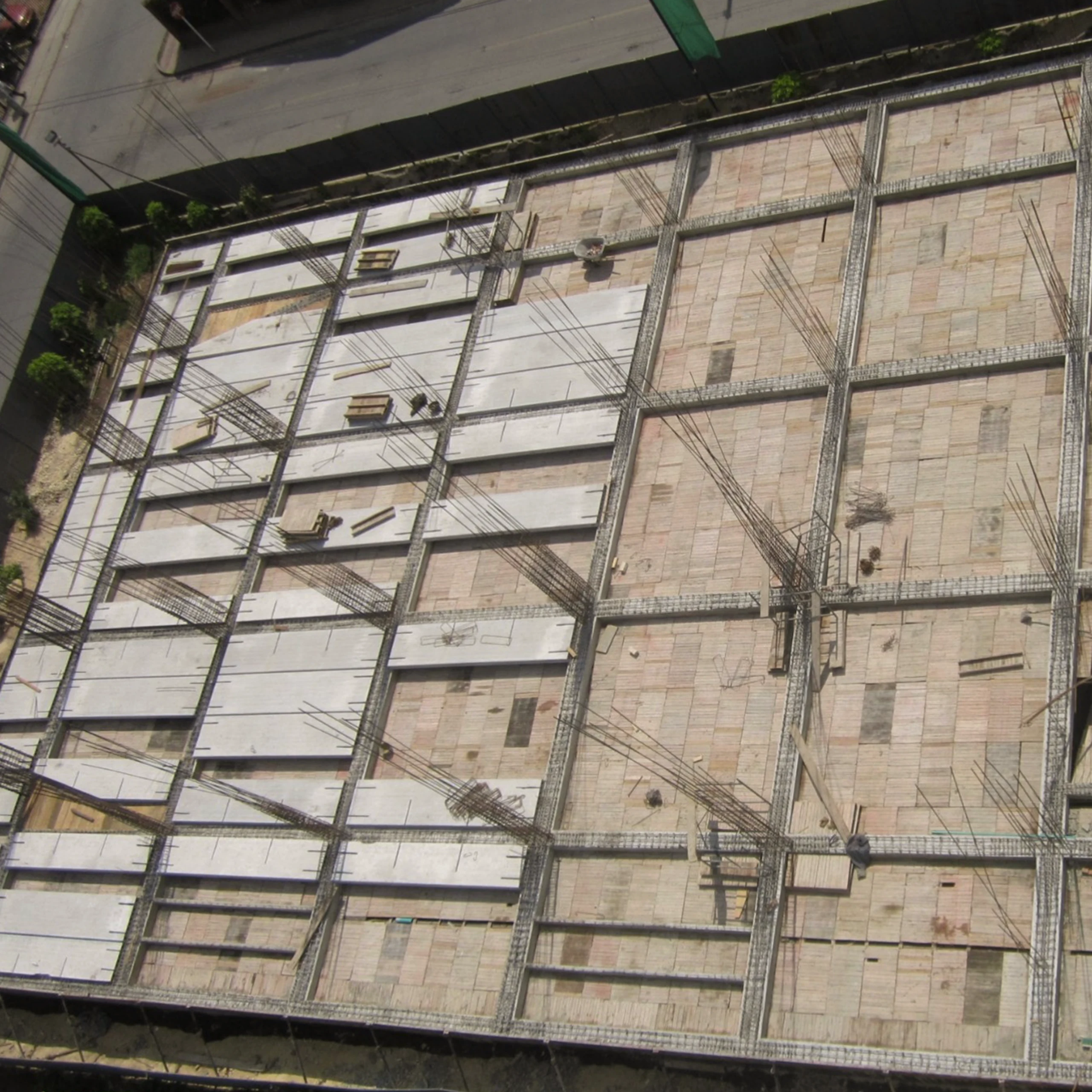 La obra en montaje, vista desde arriba: las placas alveolares llegan listas de fábrica y se apoyan sobre el pórtico; el edificio crece por ensamble más que por vaciado.