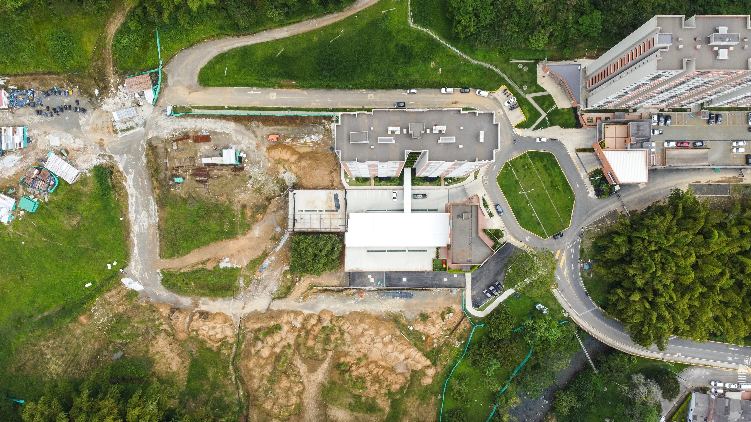 Vista cenital. Se lee la plataforma como pieza de suelo: cubre el parqueo, resuelve el acceso vehicular y devuelve una superficie usable arriba.
