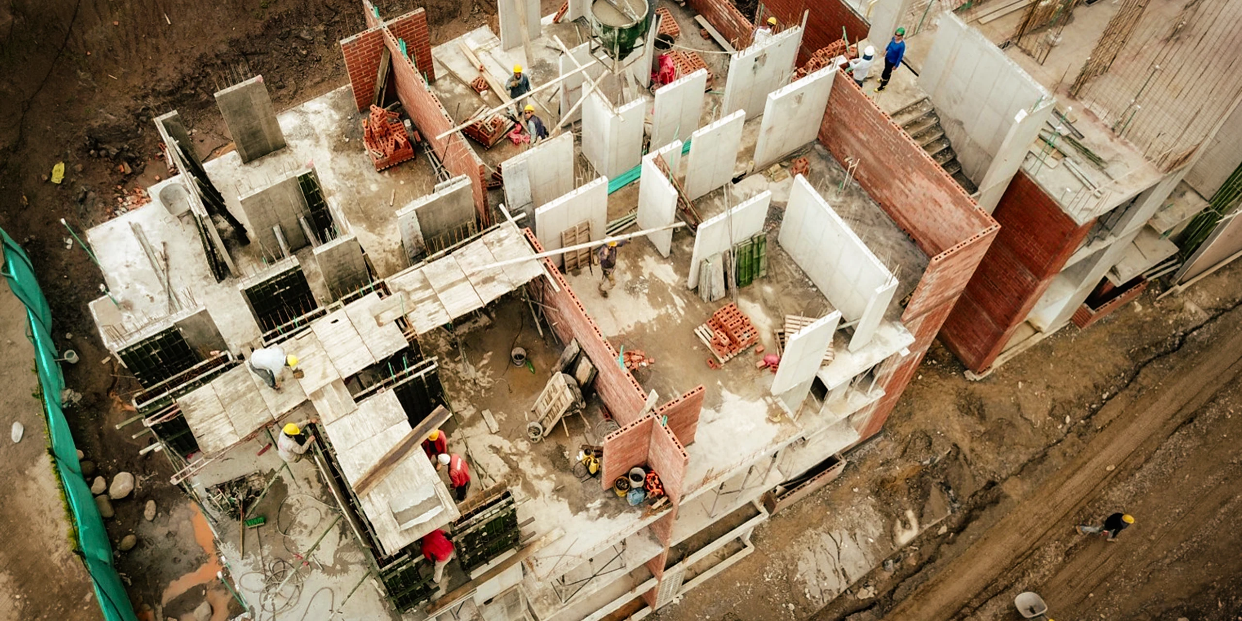 Detalle del sistema constructivo en obra: formaleta metálica, muros portantes de concreto y cerramientos de ladrillo levantándose sobre la placa.