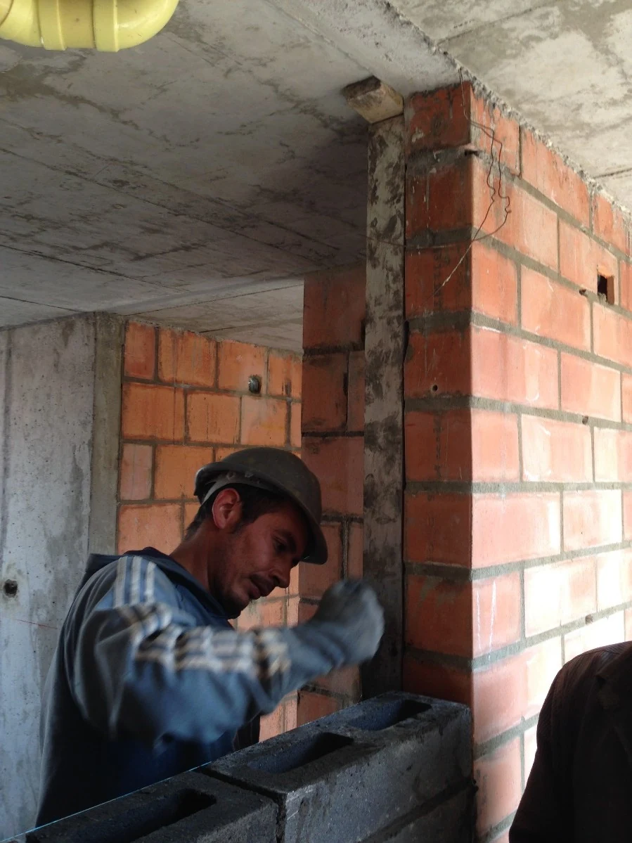 Encuentro entre la columna de ladrillo y la placa de concreto, resuelto y rematado a mano en obra.
