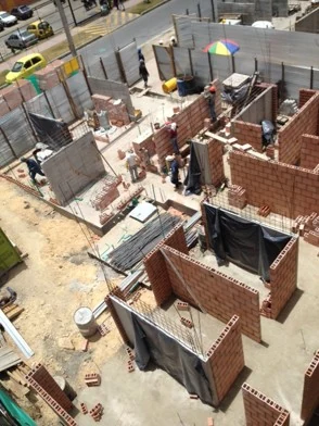 Vista en altura de la obra: los muros de ladrillo ya definen las viviendas alrededor del patio antes de la cubierta.