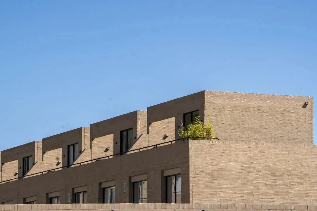 El ladrillo a la vista y los grandes vanos verticales definen la fachada sobria de las viviendas, aún en estructura.